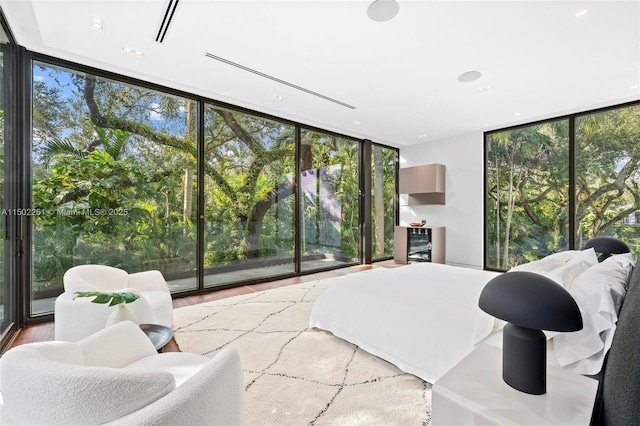 bedroom featuring access to exterior, a wall of windows, and hardwood / wood-style floors