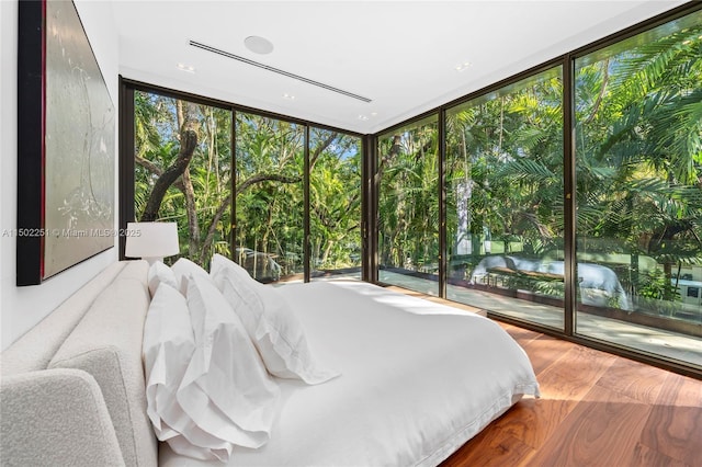 bedroom featuring expansive windows, wood-type flooring, and access to exterior