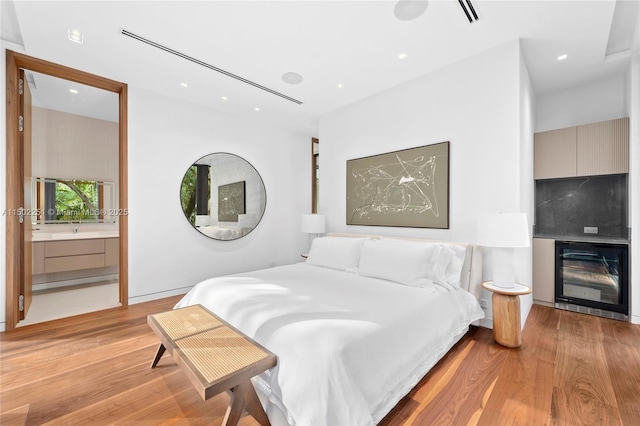 bedroom with ensuite bath and light hardwood / wood-style floors