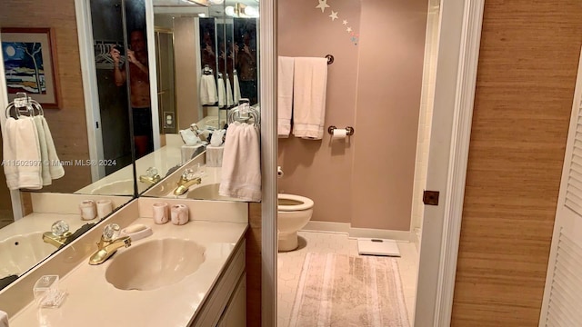 bathroom with tile patterned floors, wooden walls, vanity, and toilet