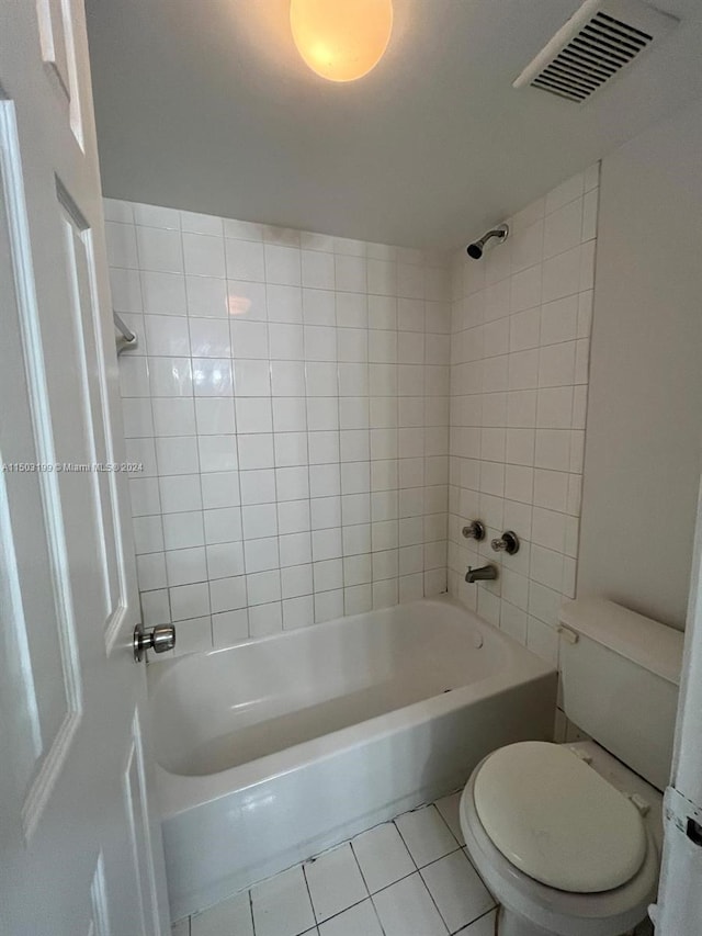 bathroom with toilet, tiled shower / bath combo, and tile patterned floors