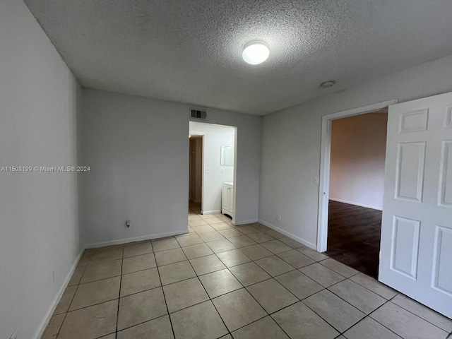 spare room with light tile patterned floors and a textured ceiling