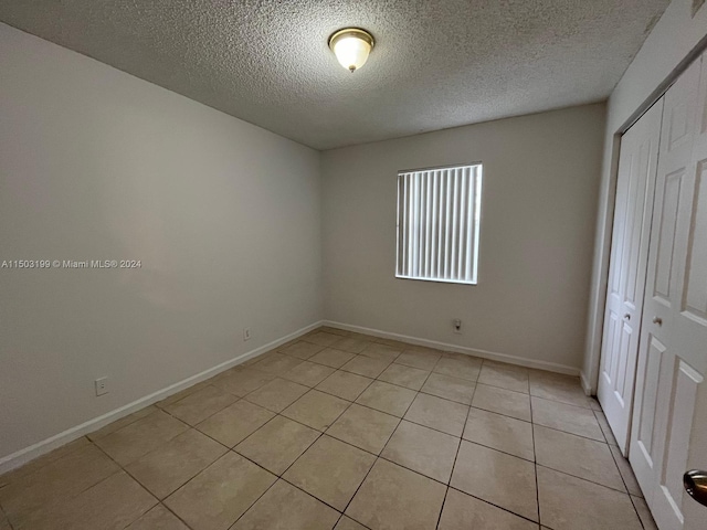 unfurnished bedroom featuring light tile patterned flooring, a textured ceiling, and a closet