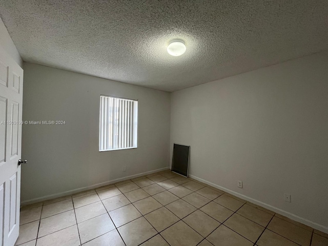 tiled spare room with a textured ceiling