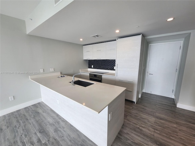 kitchen with black electric stovetop, oven, sink, dark hardwood / wood-style floors, and white cabinetry