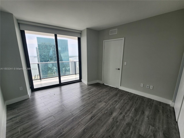 empty room with floor to ceiling windows and dark hardwood / wood-style flooring