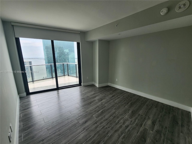 spare room with dark hardwood / wood-style flooring and a water view