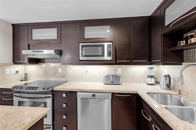 kitchen with dark brown cabinets, tasteful backsplash, sink, light stone counters, and appliances with stainless steel finishes