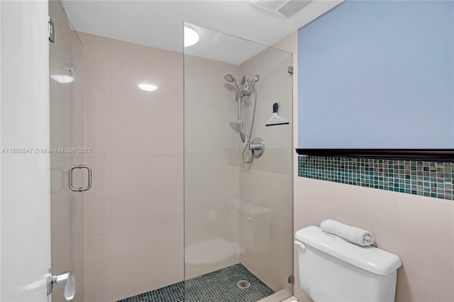 bathroom featuring toilet, an enclosed shower, and tile walls