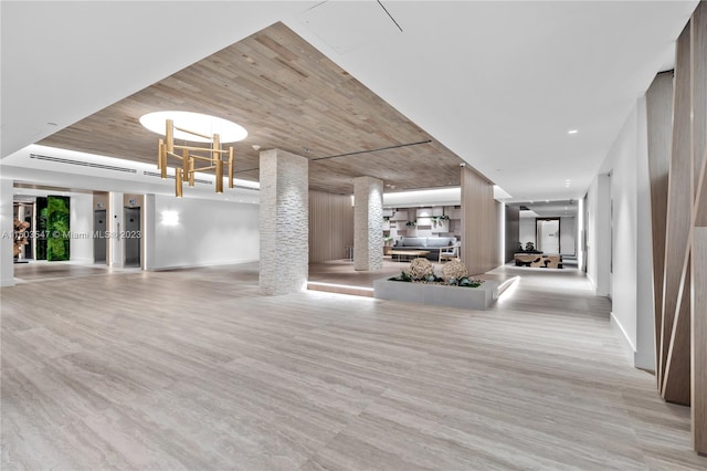 unfurnished living room featuring decorative columns, wooden ceiling, and light hardwood / wood-style floors