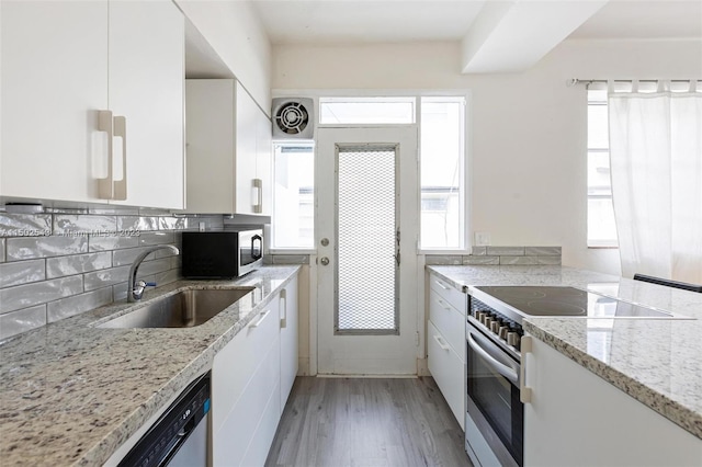 kitchen with appliances with stainless steel finishes, sink, white cabinetry, and a wealth of natural light