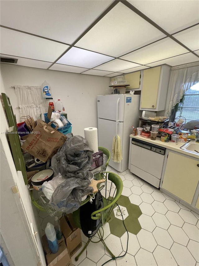 kitchen with a drop ceiling, light tile patterned floors, sink, and white appliances