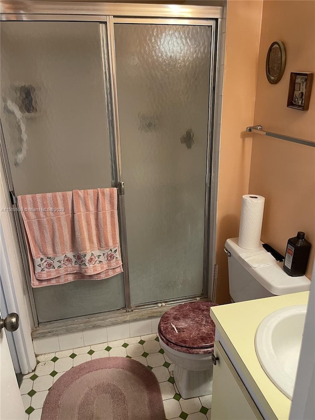 bathroom featuring vanity, walk in shower, tile patterned flooring, and toilet