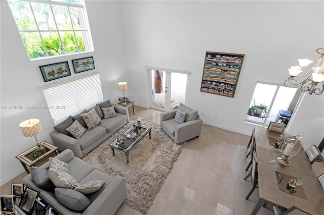 tiled living room featuring a healthy amount of sunlight, a towering ceiling, and an inviting chandelier