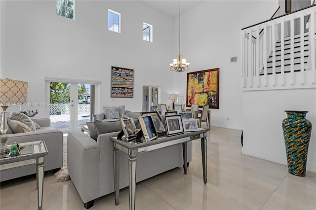 living room featuring a wealth of natural light, a notable chandelier, a towering ceiling, and light tile flooring