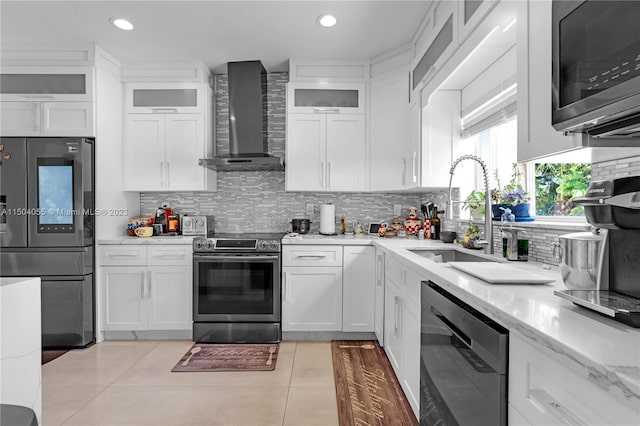 kitchen featuring appliances with stainless steel finishes, backsplash, light tile floors, and wall chimney exhaust hood