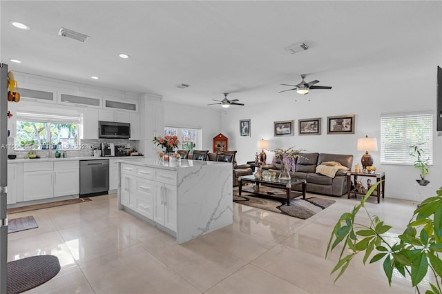 kitchen with light stone countertops, ceiling fan, stainless steel appliances, light tile floors, and white cabinetry