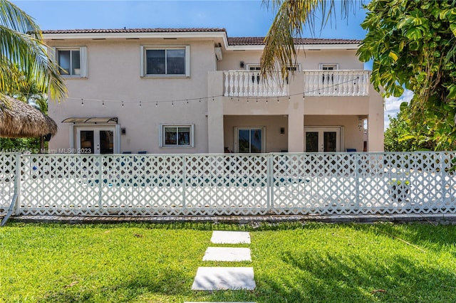 rear view of house with a lawn and a balcony