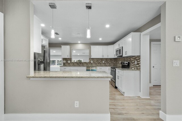 104 Ballard, Avon Park, FL 33825 - kitchen with appliances with stainless steel finishes, a peninsula, backsplash, light wood-type flooring, and light stone countertops