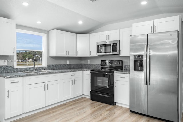 kitchen with sink, light hardwood / wood-style flooring, stainless steel appliances, and vaulted ceiling