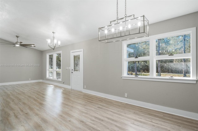 interior space with ceiling fan with notable chandelier and light hardwood / wood-style floors