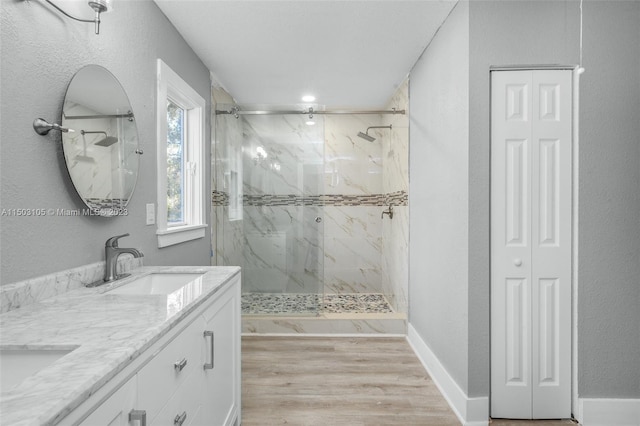 bathroom with a shower with shower door, double sink vanity, and hardwood / wood-style floors