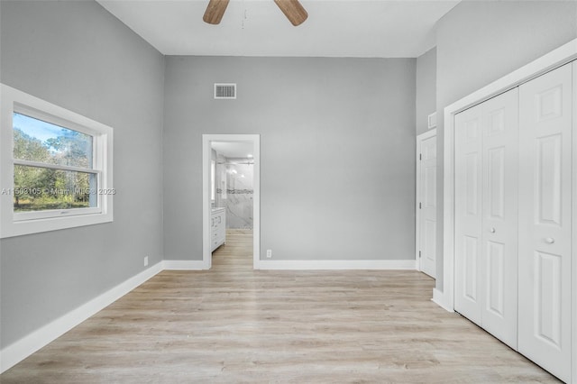 unfurnished bedroom with a closet, light hardwood / wood-style flooring, ensuite bathroom, and ceiling fan