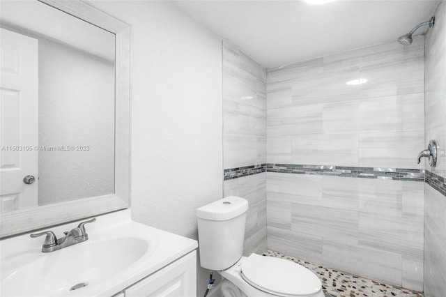 bathroom featuring vanity, a tile shower, and toilet