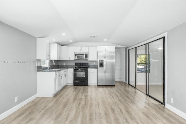 kitchen with white cabinetry, vaulted ceiling, appliances with stainless steel finishes, and light wood-type flooring