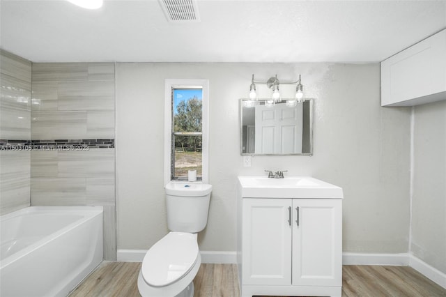 bathroom featuring wood-type flooring, a bathing tub, toilet, and vanity