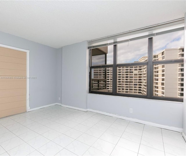 spare room with light tile patterned floors and a textured ceiling