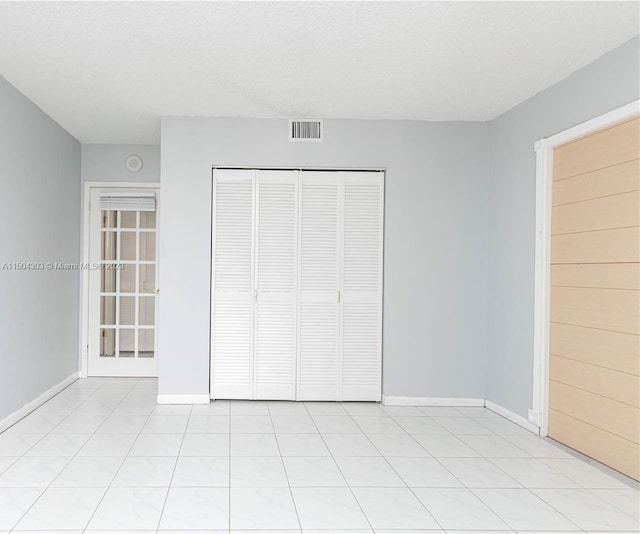 unfurnished bedroom featuring light tile patterned flooring, a closet, and a textured ceiling