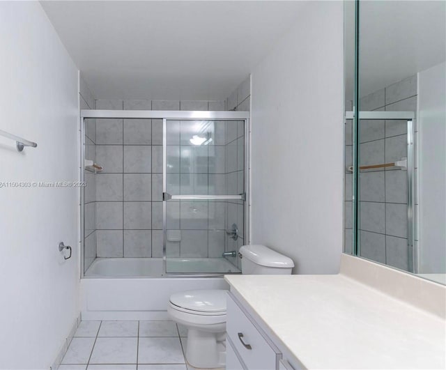 full bathroom featuring vanity, combined bath / shower with glass door, tile patterned flooring, and toilet