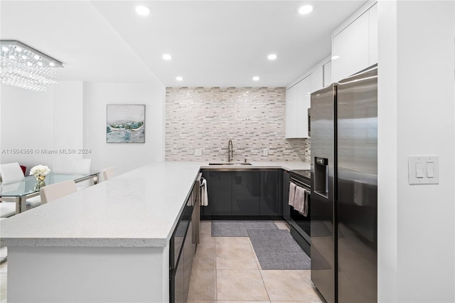 kitchen with white cabinetry, stainless steel refrigerator with ice dispenser, sink, light tile patterned floors, and backsplash