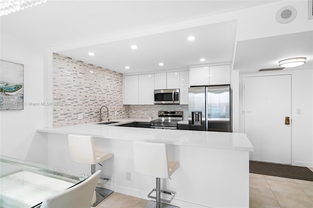 kitchen with appliances with stainless steel finishes, light tile patterned flooring, white cabinets, and kitchen peninsula