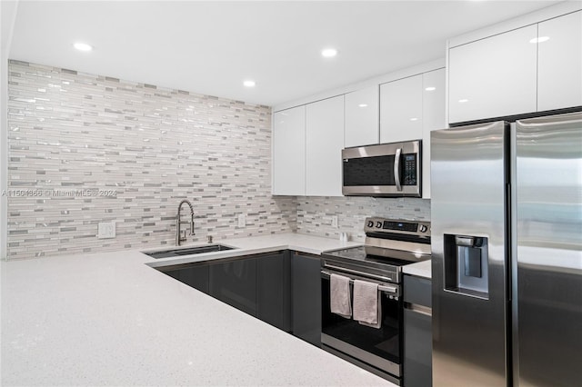 kitchen with sink, stainless steel appliances, backsplash, and white cabinetry