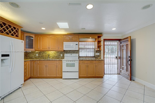 kitchen with white appliances, dark stone countertops, light tile floors, and ornamental molding