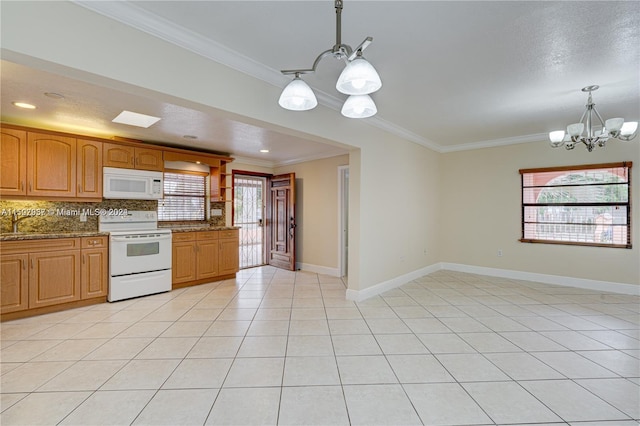 kitchen with white appliances, dark stone counters, a healthy amount of sunlight, an inviting chandelier, and decorative light fixtures