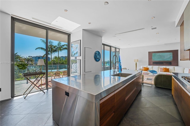 kitchen featuring expansive windows, sink, and an island with sink