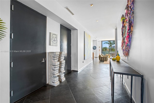 corridor featuring floor to ceiling windows and dark tile patterned flooring