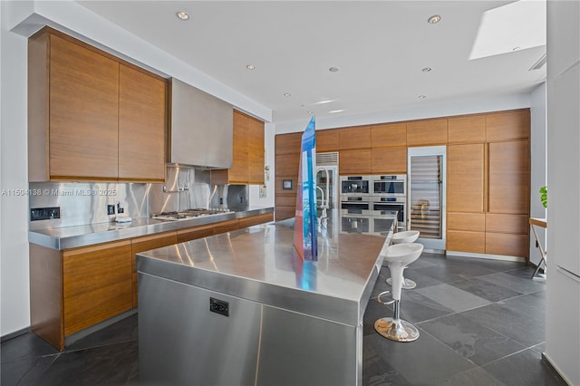 kitchen featuring a large island, tasteful backsplash, stainless steel counters, and appliances with stainless steel finishes