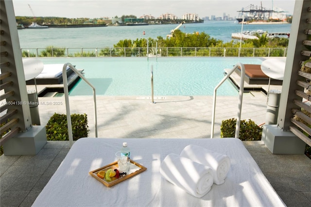 view of pool featuring a water view and a patio area