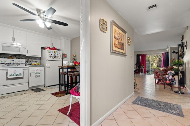 kitchen with light tile patterned flooring, ceiling fan, tasteful backsplash, white cabinets, and white appliances