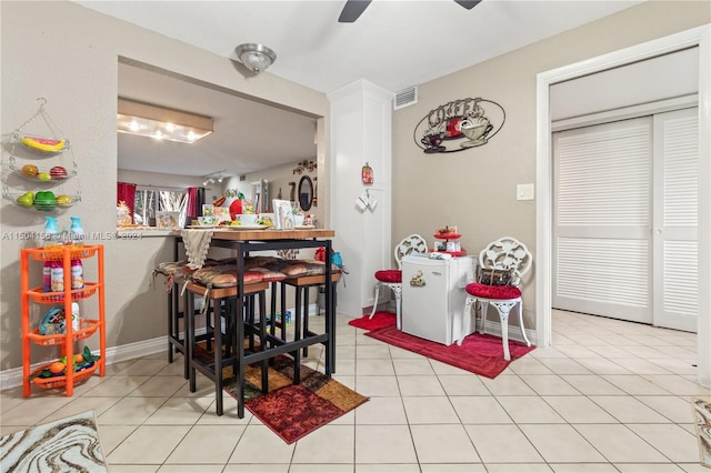 dining space featuring light tile patterned flooring, visible vents, baseboards, a ceiling fan, and a dry bar