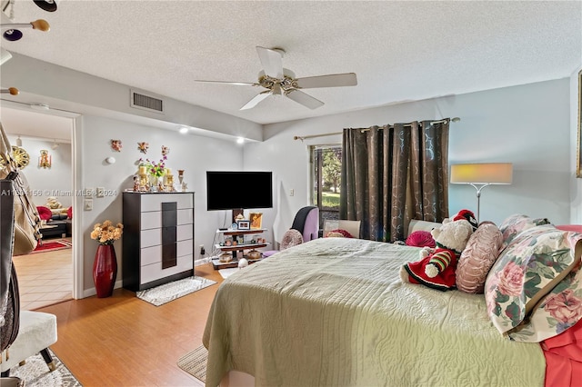 bedroom featuring a ceiling fan, light wood-style flooring, visible vents, and a textured ceiling