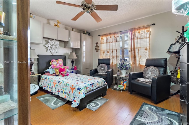 bedroom with light wood-type flooring, ceiling fan, and a textured ceiling