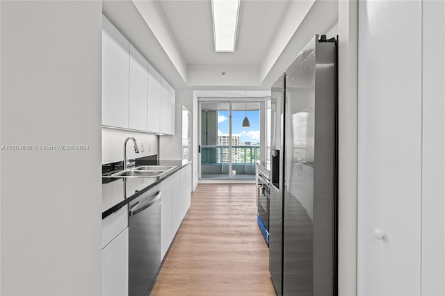 kitchen featuring white cabinetry, dishwasher, light hardwood / wood-style floors, and sink