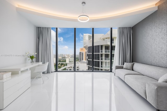 tiled living room with a tray ceiling and floor to ceiling windows