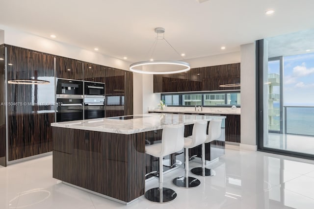 kitchen with a center island, light tile flooring, dark brown cabinets, and pendant lighting