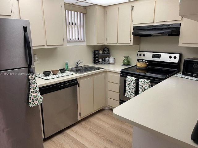 kitchen with cream cabinets, stainless steel appliances, light wood-type flooring, and sink